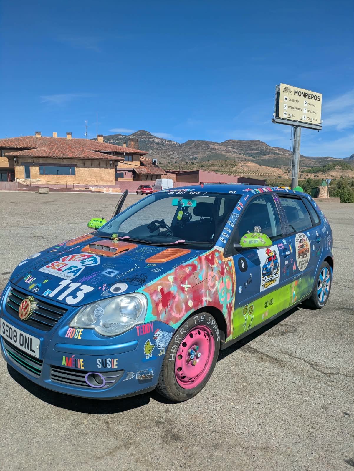 The sticker-covered Polo parked in Spain, mountains behind