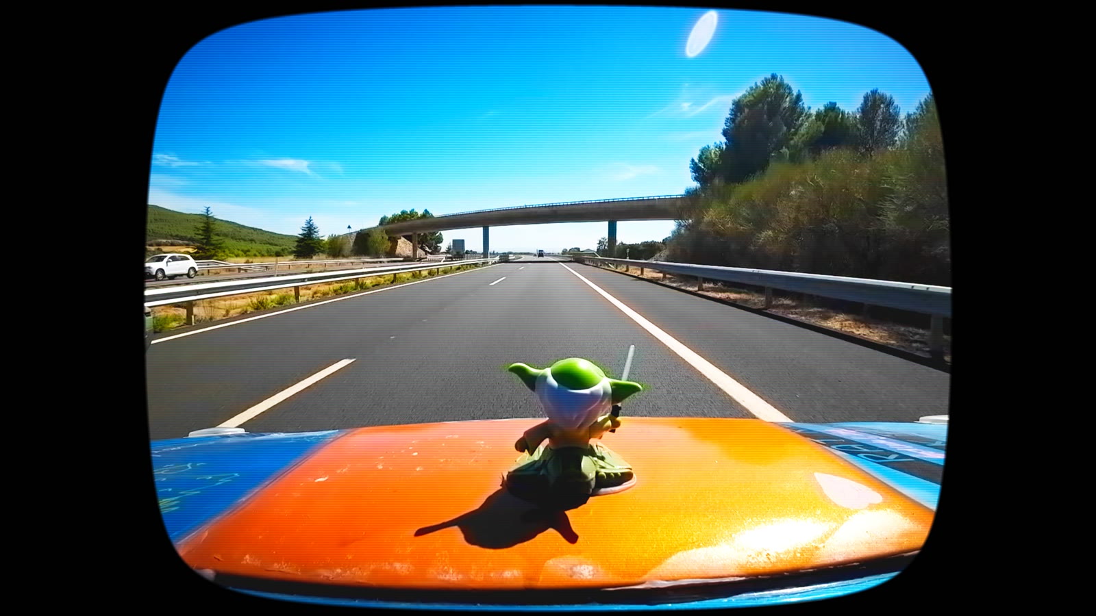 A Yoda figure riding on the bonnet of the rally car, motorway ahead
