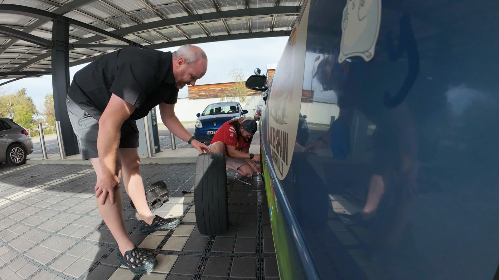 A wheel off at a service station, one of the team crouched by the car