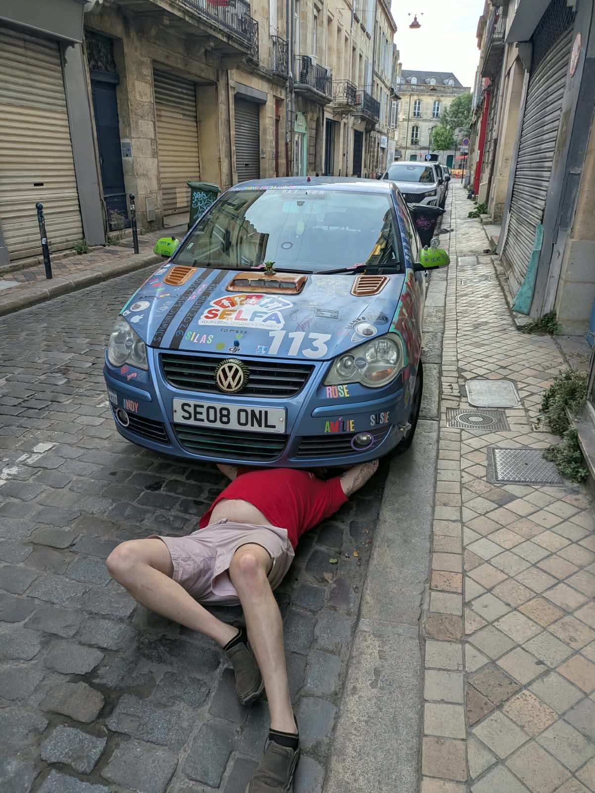 Lying under the front of the car on a cobbled street in Bordeaux