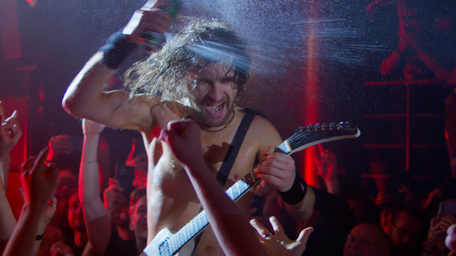 A guitarist performing on stage under blue lights
